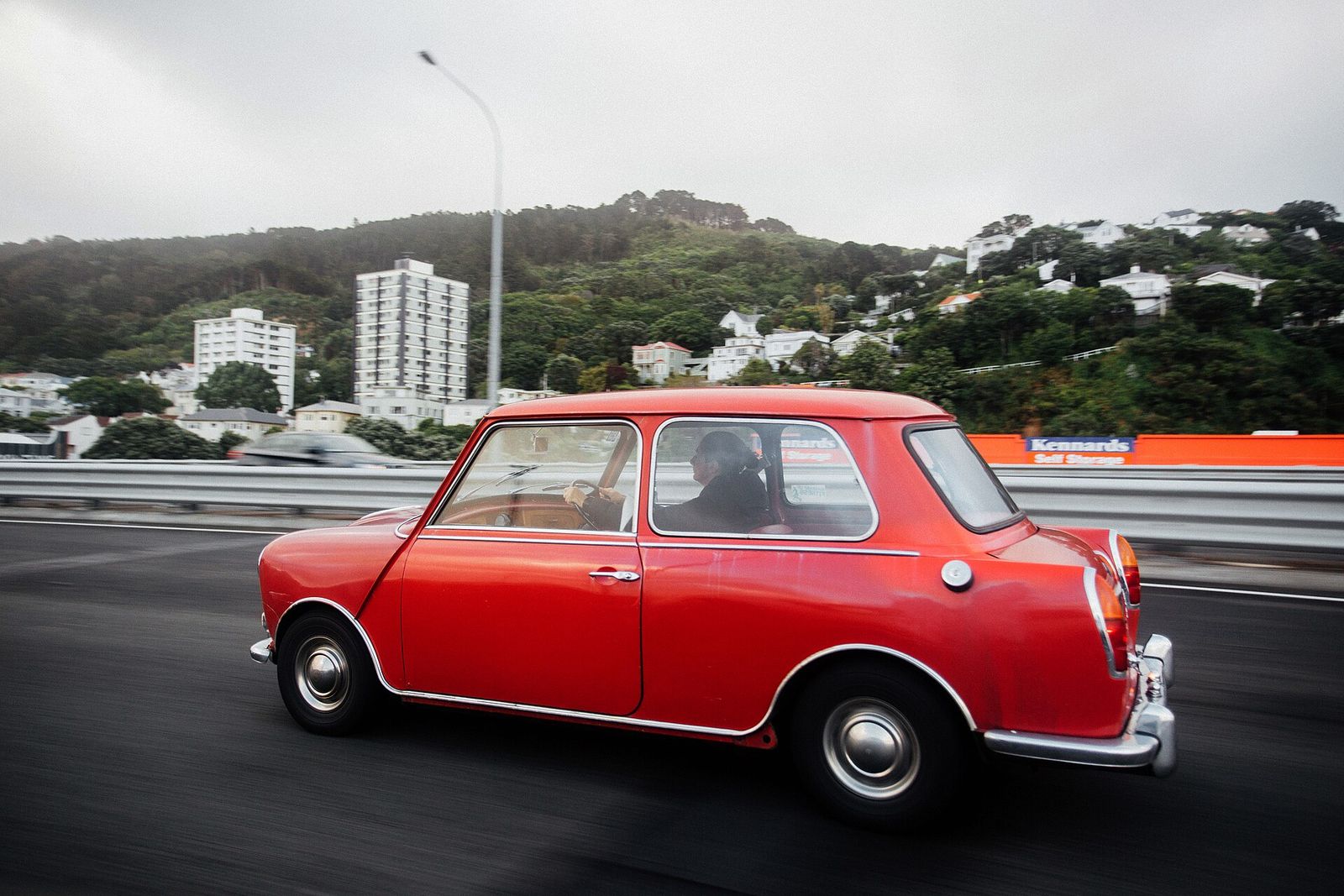 A red classic hatchback with chrome trim on a city road